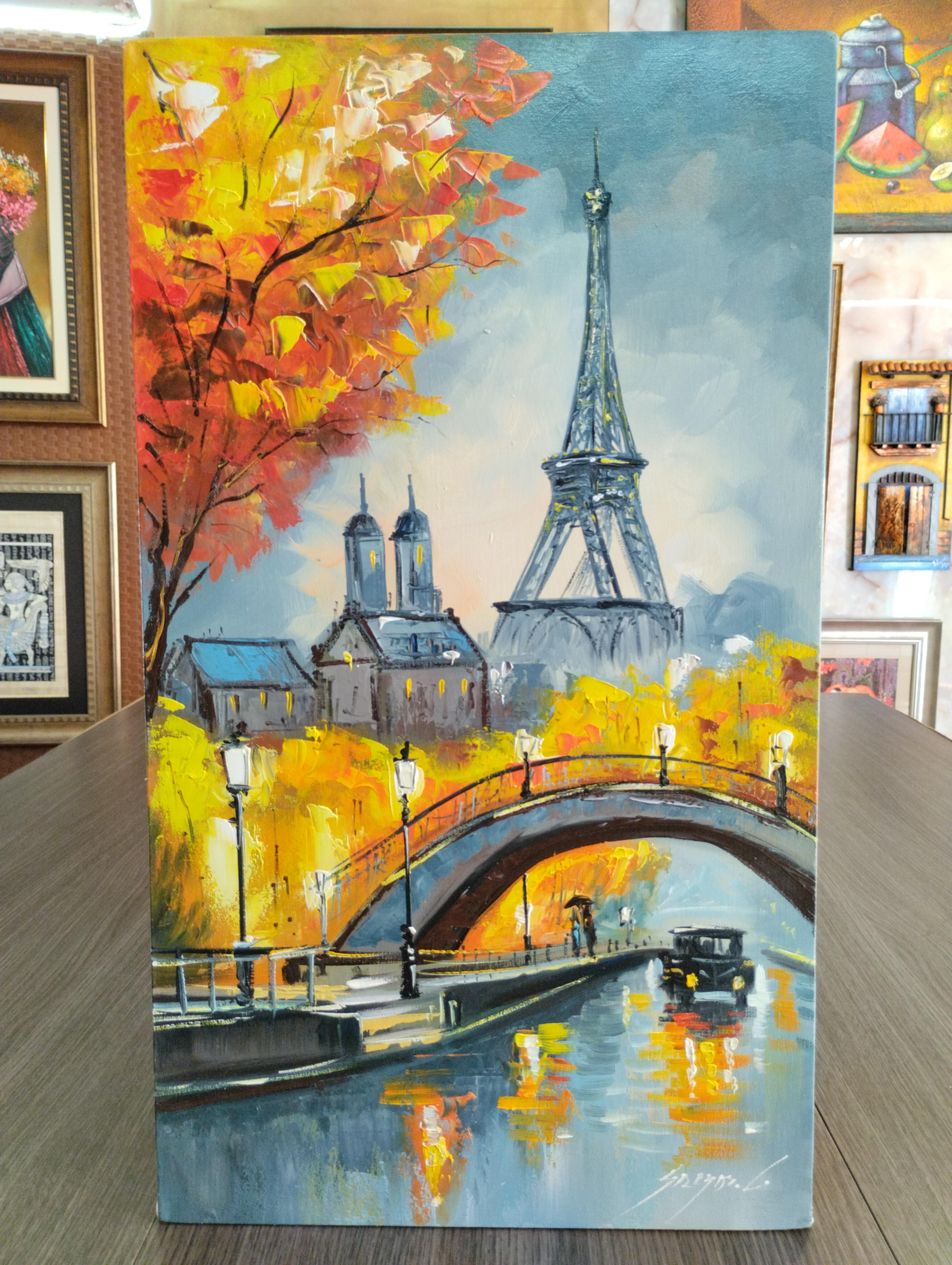 Torre Eiffel. Escena urbana con la Torre Eiffel al fondo, puente curvo sobre un canal y arboles otonales en tonos calidos reflejados en el agua.