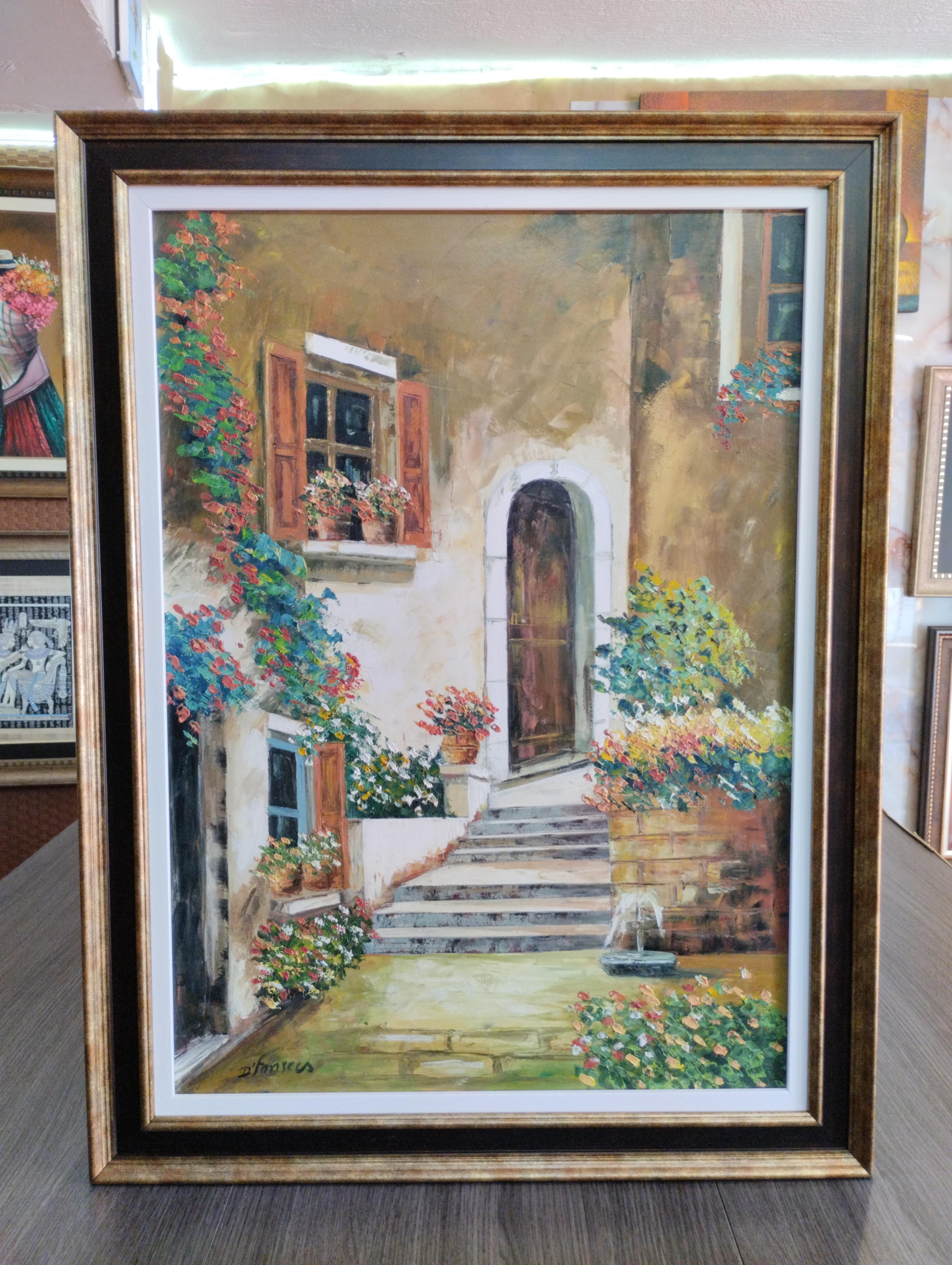 Umbral de luz y flores. Fachada calida con puerta arqueada y ventanas con flores, rodeada de vegetacion; el marco dorado resalta la obra con un acabado elegante y clasico.